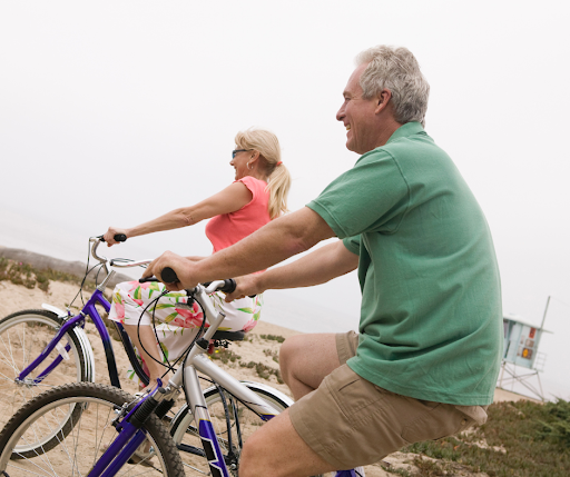 A photo of a middle aged couple riding bicycles on the beach after a successful round of cardiopumonary rehabilitation at Iowa Specialty Hospitals and Clinics.